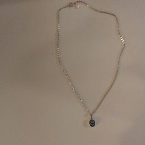 Silver necklace with flower charm on bottom of necklace.